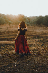 Rear view of woman standing on field against sky