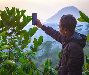 Side view of boy standing by plants