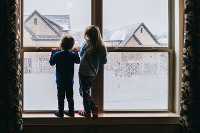 Rear view of girl looking through window