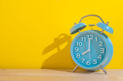 Close-up of clock on yellow wall