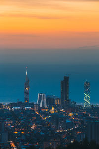 Illuminated cityscape against sky during sunset