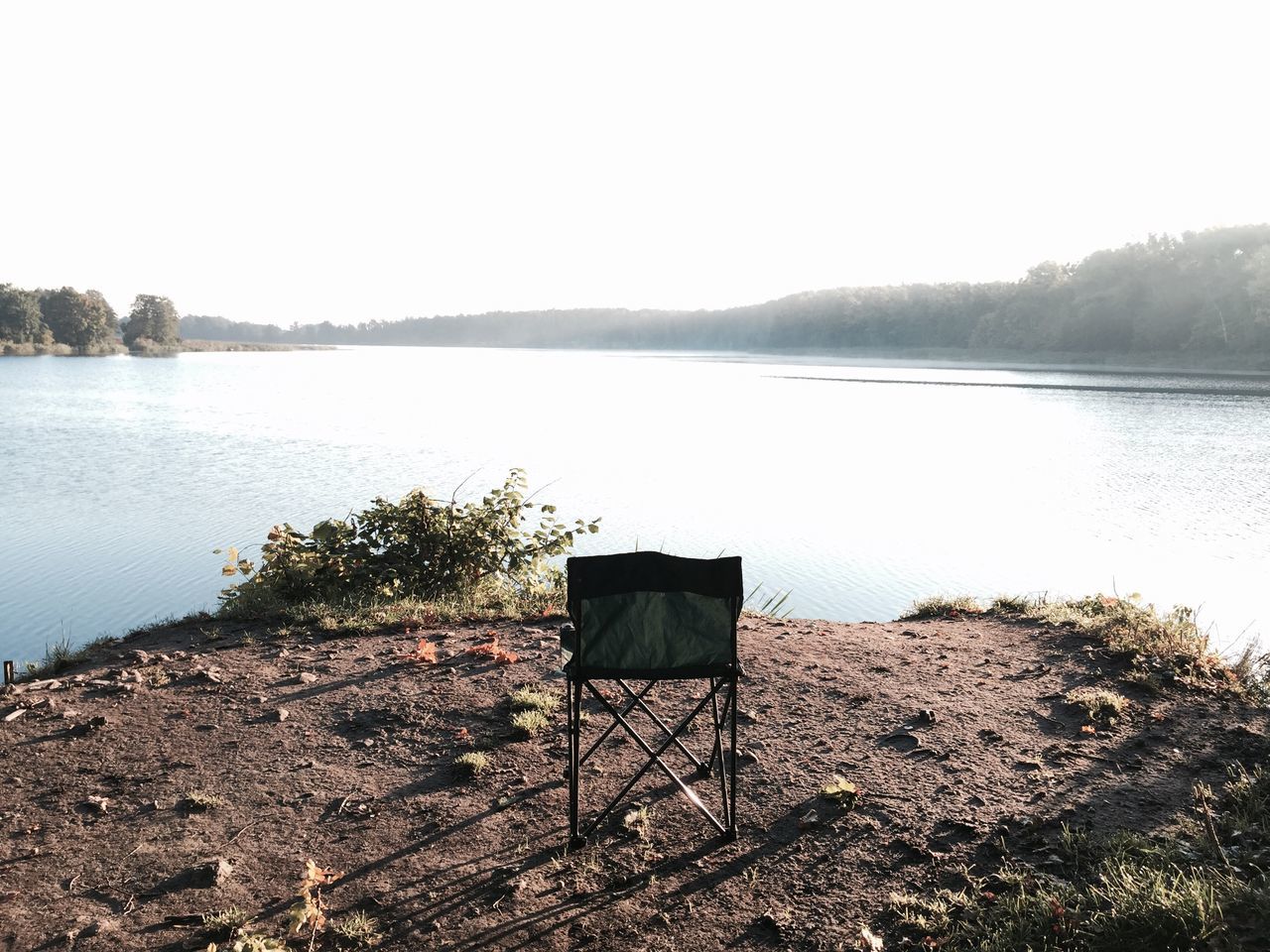 water, lake, tranquil scene, tranquility, clear sky, scenics, copy space, lakeshore, tree, non-urban scene, nature, beauty in nature, calm, solitude, day, sky, outdoors, riverbank, no people, countryside, remote, in front of, shore