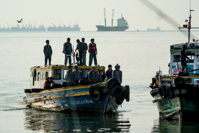 People on boat in sea against sky