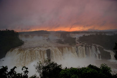 Scenic view of waterfall against sky during sunset