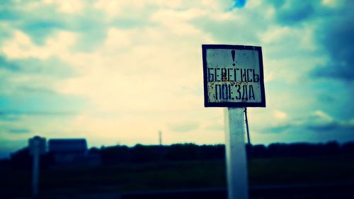 Low angle view of road sign against cloudy sky