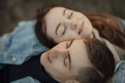 Happy young loving young couple relaxing with eyes closed, head on shoulder