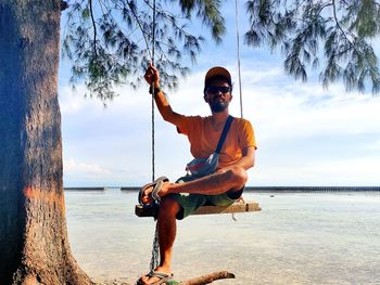 Man sitting on beach against sky