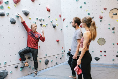 Mature instructor teaching students about bouldering in gym