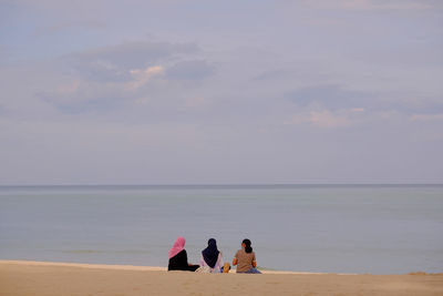 Rear view of women on beach against sky