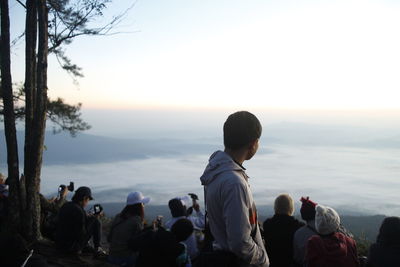 People looking at sea against sky