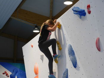 Full length of girl climbing wall
