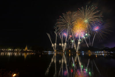 Firework display over lake at night