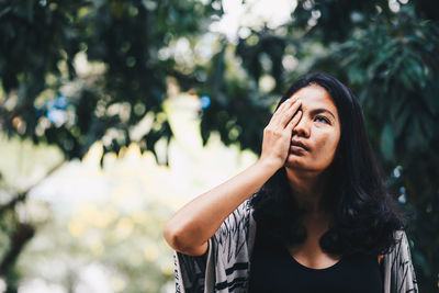 Mid adult woman covering eye in park