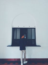 Rear view of young man standing against wall