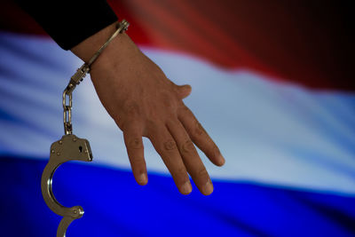Cropped hand with handcuffs against dutch flag