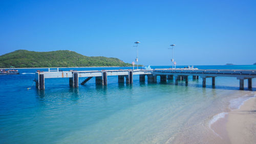 Pier over sea against clear blue sky