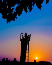 Silhouette man standing by tree against sky during sunset