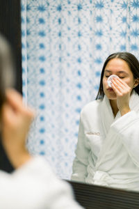 Woman in front of a mirror cleaning her face