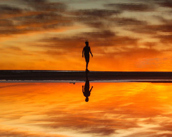 Full length of silhouette woman standing on beach against sky during sunset