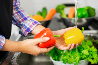Midsection of woman holding bell peppers at home