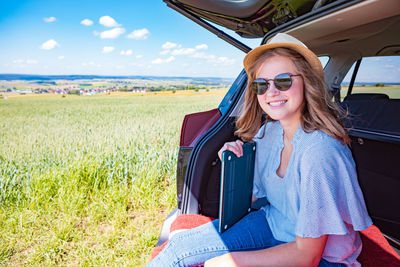 Portrait of smiling young woman sitting on field