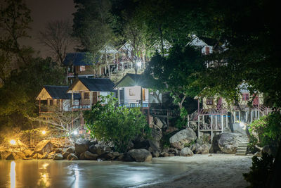 View of illuminated buildings by river at night