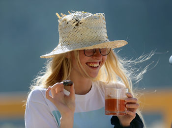 Young woman wearing hat holding drink