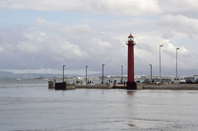 Lighthouse by sea against sky