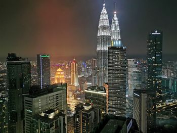 Illuminated buildings in city against sky at night