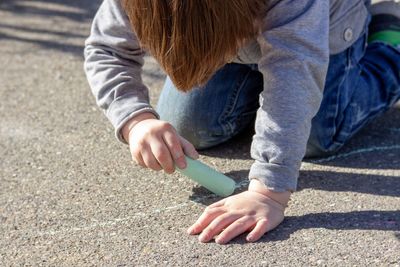 Boy drawing on road with chalk in city