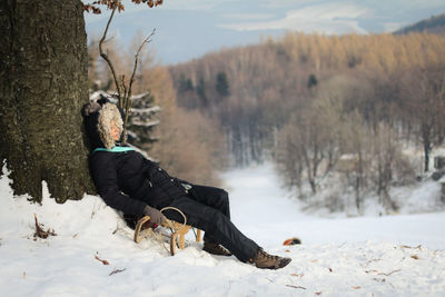 Full length of woman with sled on snowy field