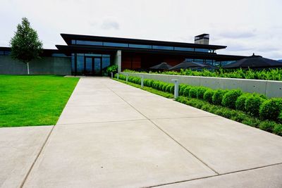 Footpath by lawn and building against sky