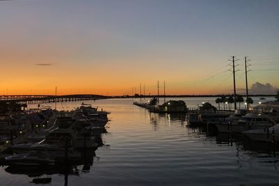 Boats moored in harbor at sunset