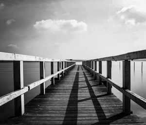 Wooden footbridge over water against sky