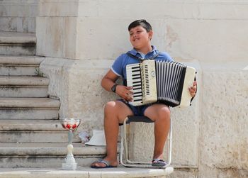 Full length of boy sitting on wall