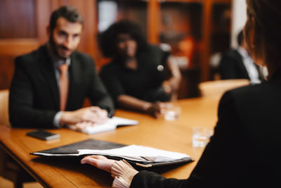 Businesswoman holding contract document discussing with financial advisors in meeting