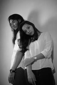 Portrait of a smiling young woman standing against the wall