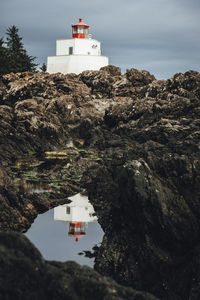 Building on rock by sea against sky