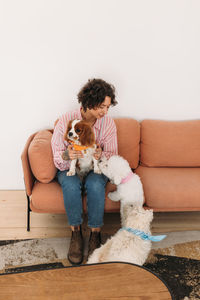 Young woman with teddy bear while sitting on sofa against white background