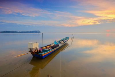 Boat moored on sea against sky during sunset