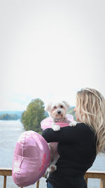 Woman with dog against clear sky