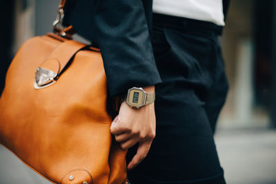Midsection of businesswoman with orange purse standing in city