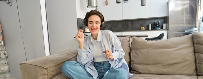 Young woman using phone while sitting on sofa at home