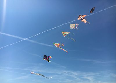 Low angle view of kites flying against sky
