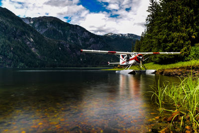 Seaplane on lakeshore against mountains