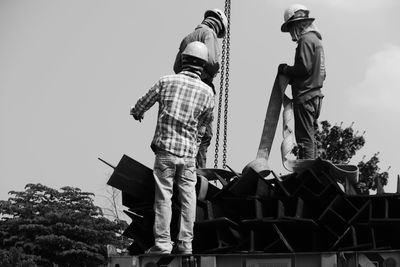 Low angle view of men standing against sky