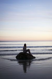 Woman looks to the ocean at sunset