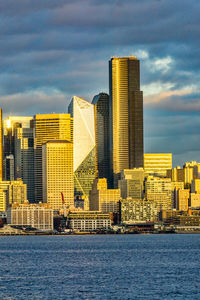 The setting sun makes a section of the city of seattle shine across elliott bay.