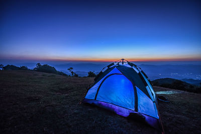 Tent on field against sky at sunset