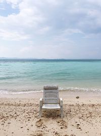 Chair on beach against sky